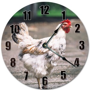 May include: Round wall clock featuring a white chicken with brown and tan markings, a red comb, and black clock hands. The clock face has black numerals and a green background.