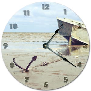 May include: Round wall clock featuring a beach scene with a boat, anchor, and chain. The clock face displays the numbers 1 through 12 in a light gray font. The clock hands are black.