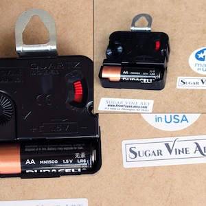 a black electronic device, possibly a clock, with a battery and a label indicating it is made in the USA.