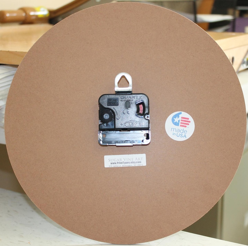 a clock with a brown background, a black clock face, and a white label with text.