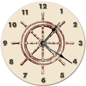 Peut inclure: Une horloge murale ronde sur le thème nautique. Le cadran est beige clair avec des chiffres marron foncé et une illustration détaillée d'une barre de navire au centre. Les aiguilles de l'horloge sont noires.