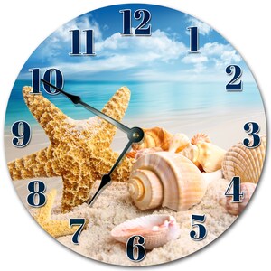 May include: A round clock with a beach scene featuring a starfish, seashells, and sand. The clock face has blue numbers on a white background. The clock hands are black.