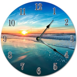May include: Round wall clock featuring a scenic beach sunset. The clock face displays a vibrant image of the ocean, sky, and sun, with black hands and black numerals. The clock is a decorative item for home decor.