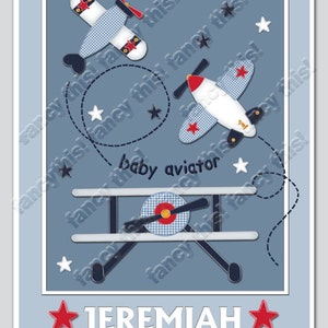 May include: A baby-themed artwork featuring three toy airplanes in blue, white, and red. The planes are decorated with stars and gingham patterns. The text "baby aviator" and the name "Jeremiah" are also included.