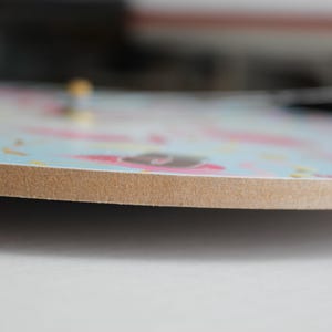 A close-up view of a colorful, patterned clock face with a wooden border.
