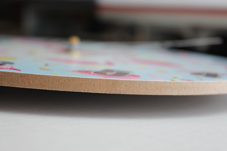 A close-up view of a colorful, patterned clock face with a wooden border.