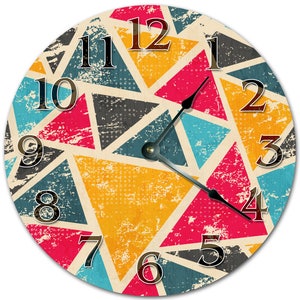 May include: Round wall clock with a colorful geometric design. The clock face features a pattern of triangles in shades of red, yellow, blue, and gray, with black numerals and hands. The clock has a distressed, vintage look.