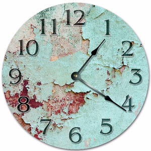 May include: Round wall clock with a distressed, textured face. The clock face features a teal and red color scheme with black numerals and hands. The clock's design gives it a vintage, weathered appearance.