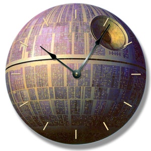 May include: A round wall clock featuring a detailed illustration of the Death Star from Star Wars. The clock face is a mix of purple, gold, and gray, with black clock hands and gold-colored hour markers. A unique decorative piece.
