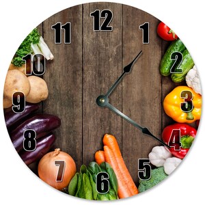 May include: Round wall clock featuring a wooden background with black numerals and clock hands. The clock face is decorated with various fresh vegetables, including tomatoes, cucumbers, peppers, carrots, and potatoes. A unique kitchen or dining room decor item.