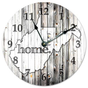 May include: Circular wall clock with a weathered wood effect. The clock face displays the white outline of West Virginia, with the word "home." in the centre. Black hands show the time. Numbers are in a simple, bold font.