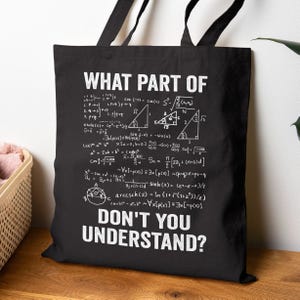 May include: A black tote bag featuring white printed text that reads "WHAT PART OF" at the top and "DON'T YOU UNDERSTAND?" at the bottom. Between the text are various white mathematical formulas, geometric triangles, and algebraic equations.
