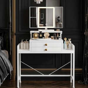 May include: A white vanity table with a tri-fold lighted mirror. The table has two drawers with gold knobs and a shelf for cosmetics and accessories. The room features black paneling, a chandelier, and a dark rug.