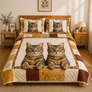 May include: A quilted bedspread and two pillowcases featuring a large image of two tabby cats with green eyes. The bedspread has a patchwork design in cream, brown, and yellow tones. The pillowcases have a single cat image.