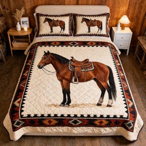 May include: A cream-coloured quilt set with a detailed illustration of a brown horse with a saddle. The quilt and two pillowcases have a geometric border in shades of brown, black, and orange. The bedding set is designed for a bed.