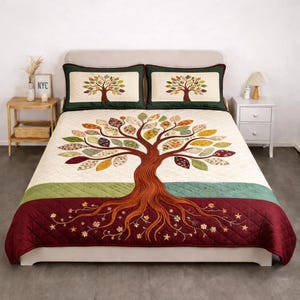 Puede incluir: Juego de cama acolchado con temática de árbol, con una colcha color crema con un gran diseño de árbol marrón y hojas coloridas. La colcha tiene un borde burdeos con detalles florales y de estrellas. Incluye dos fundas de almohada a juego.
