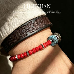 May include: A close-up of a wrist adorned with two bracelets. The first is a dark brown leather cuff with an embossed geometric pattern. The second is a red beaded bracelet with silver accents and a turquoise and silver bead. The text "LIJIXUAN" is visible.