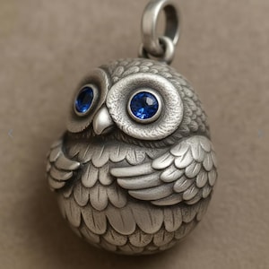 May include: A silver owl pendant with blue gemstone eyes. The owl is detailed with textured feathers and a loop for a chain. The pendant is a unique piece of jewelry, perfect for owl lovers.