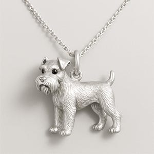 May include: A silver-colored pendant necklace featuring a detailed miniature Schnauzer dog charm. The dog is depicted in a standing pose with textured fur, a long beard, and small, dark eyes. The necklace chain is also silver.