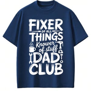 May include: Navy blue t-shirt with white text that reads "FIXER OF ALL THINGS Knower of stuff DAD CLUB". The design includes illustrations of tools and a coffee mug. A crew neck, short-sleeved shirt.