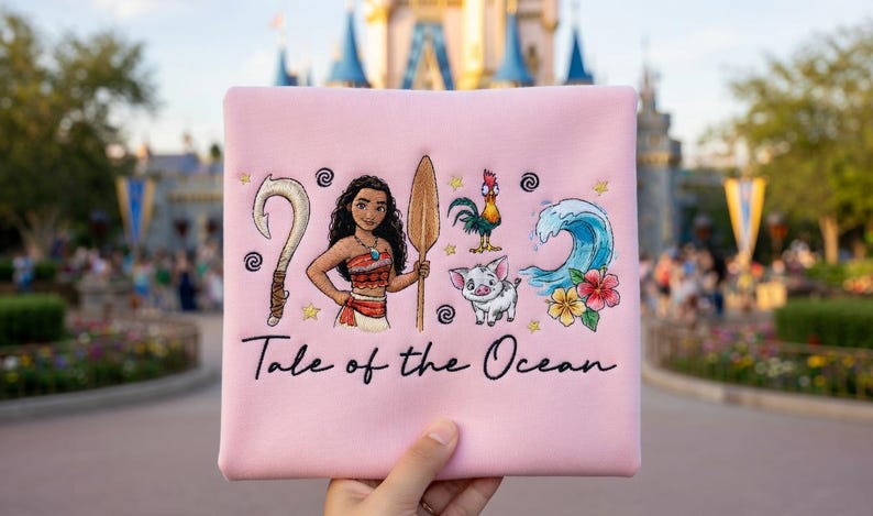 Pu&ograve; includere: Un tessuto quadrato rosa con un disegno ricamato raffigurante una donna, un gancio, una pagaia di legno, un gallo, un maiale, un'onda e fiori. Il testo "Tale of the Ocean" &egrave; scritto sotto.