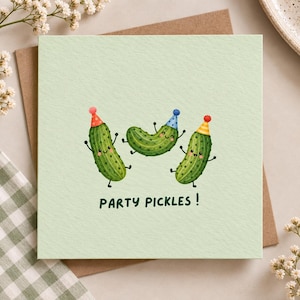 May include: A square greeting card with a light green background featuring three illustrated green pickles wearing colorful polka-dot party hats. The pickles have smiling faces and arms and legs. The text PARTY PICKLES! is printed in dark green.