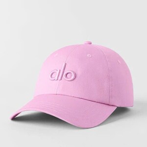 Puede incluir: Gorra de b&eacute;isbol rosa claro con visera curva. La gorra presenta las letras "alo" bordadas en la parte delantera. El sombrero est&aacute; hecho de una tela suave y tiene una corona redondeada.