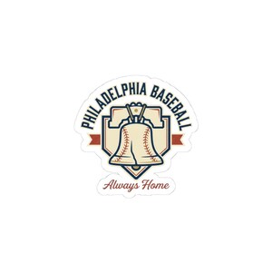 Könnte beinhalten: Ein gestanzter Aufkleber mit einer Grafik der Liberty Bell, die mit Baseballnähten gestaltet ist. Der Text PHILADELPHIA BASEBALL wölbt sich oben, und Always Home steht in roter Schreibschrift unten, alles in Marineblau, Rot und Creme.