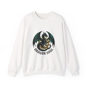 Könnte beinhalten: Ein weißes Langarm-Sweatshirt mit einer zentralen Grafik eines dunkelgrünen Drachen mit ausgebreiteten Flügeln, der sich um ein goldenes kreisförmiges Emblem windet. Unter dem Drachen steht der Text DRAGON SOUL in fetter, dunkler Schrift.
