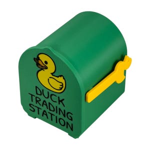 May include: A green, duck-shaped mailbox with a yellow duck graphic and the words "Duck Trading Station." The mailbox has a yellow handle. The design is whimsical and playful.