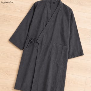 May include: A dark gray linen robe with a wrap-around design, featuring a tie closure at the waist and a front pocket. The robe has wide sleeves and a V-neckline. The text "CozyHavenCove" is in the top left corner.