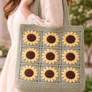 May include: A handmade crochet tote bag in a square shape, featuring a repeating pattern of sunflowers. The sunflowers have yellow petals and brown centers, set against a light green background. The bag has a matching green handle.