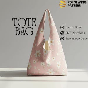 May include: A pink tote bag with a white floral pattern. The bag has a triangular shape and a single handle. The words "TOTE BAG" are printed in large, black letters. The image also includes text that says "PDF SEWING PATTERN" and lists instructions, PDF download, and step-by-step guide.