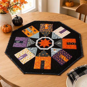 May include: An octagonal quilted table topper featuring a central orange star surrounded by various Halloween-themed fabric patches in black, orange, purple, and white. The quilt displays patterns of ghosts, pumpkins, and candy with black stitching.