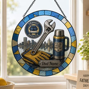 May include: Round stained glass window art with a transit service logo, wrench, thermos, and work gloves. The window art has a blue and yellow border and a cityscape background. The thermos reads "Fueling Heroes Every Day". A small plaque reads "Dad Name".