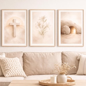Könnte beinhalten: Drei gerahmte Aquarelldrucke mit religiösen Themen. Die Drucke zeigen ein Kreuz, Lilien und ein leeres Grab. Das Kunstwerk wird über einem beigen Sofa mit dekorativen Kissen und einem Holztisch ausgestellt.