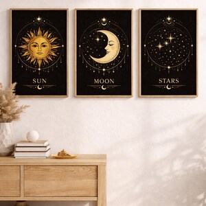 Könnte beinhalten: Set aus drei gerahmten Kunstdrucken mit Himmelsmotiven. Jeder Druck zeigt ein goldenes Design auf schwarzem Hintergrund. Die Drucke zeigen Sonne, Mond und Sterne, mit den Wörtern "SUN", "MOON" und "STARS" darunter.