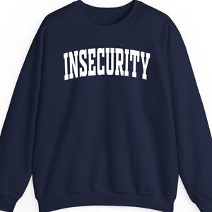 Könnte beinhalten: Ein marineblaues Sweatshirt mit dem Wort "INSECURITY" in weißen, fetten Großbuchstaben auf der Brust. Das Sweatshirt hat einen Rundhalsausschnitt und lange Ärmel, geeignet für den täglichen Gebrauch.