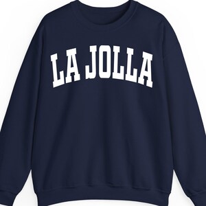 May include: Navy blue sweatshirt with the white text "LA JOLLA" across the chest. The sweatshirt has a crew neck and long sleeves. The text is in a bold, collegiate-style font.