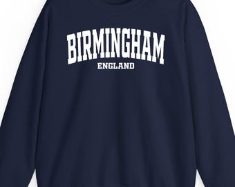 以下が含まれることがあります： 胸に大きな白いブロック体で「BIRMINGHAM」の文字がプリントされたネイビーブルーのスウェットシャツ。下に「ENGLAND」とプリントされています。スウェットシャツはクルーネックと長袖です。