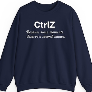 Puede incluir: Sudadera azul marino con el texto blanco "CtrlZ" y la frase "Because some moments deserve a second chance." La sudadera tiene cuello redondo y mangas largas.