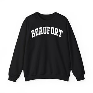 May include: Black crew neck sweatshirt with the word "BEAUFORT" printed in white, arched lettering. The sweatshirt is a solid black color and has long sleeves. The text is centered on the chest.