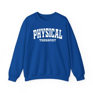 K&ouml;nnte beinhalten: Ein k&ouml;nigsblaues Sweatshirt mit dem wei&szlig;en Aufdruck "PHYSICAL THERAPIST" in Blockbuchstaben. Der Text ist mittig auf der Brust platziert. Das Sweatshirt hat einen Rundhalsausschnitt und lange &Auml;rmel.