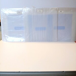 May include: Three white plastic-wrapped packages with blue labels. The labels have the text "The Original" on them.