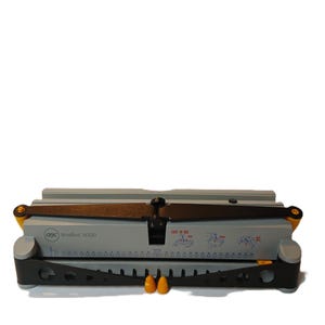 May include: A gray and black WireBind W200 machine with yellow accents. The machine has a brown handle and two orange pegs. The text "WireBind W200" and "EASY TO USE" are visible on the machine.