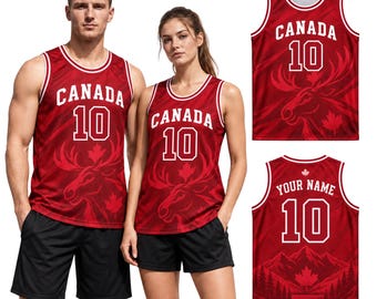 May include: A red basketball jersey featuring the text CANADA and the number 10 in white, with a graphic of a moose head and maple leaves. The back of the jersey displays the text YOUR NAME above the number 10 and a mountain landscape graphic.