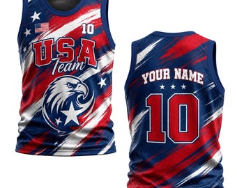 May include: A sleeveless jersey featuring a red, white, and blue brushstroke pattern. The front displays a bald eagle graphic, the text USA Team, a small American flag, and the number 10. The back shows the text YOUR NAME and the number 10.