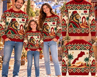 May include: A cream-coloured long-sleeve sweater featuring a red and green geometric pattern, a lion graphic with a red fez, and the text 'Your Name'. The back displays a map of Morocco, palm trees, and desert architecture in red and green.