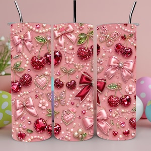 May include: A cylindrical tumbler with a pink background featuring a repeating pattern of red crystal cherries, pink satin bows, pearl strands, sparkling butterflies, and heart-shaped gems. The tumbler includes a thin metal straw at the top.