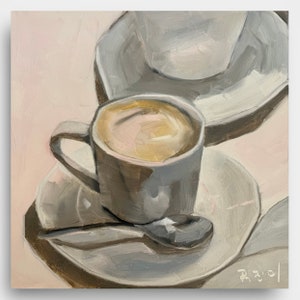 May include: A close-up of a gray coffee cup with a saucer and a spoon. The cup is filled with coffee and the saucer is on a light pink background.